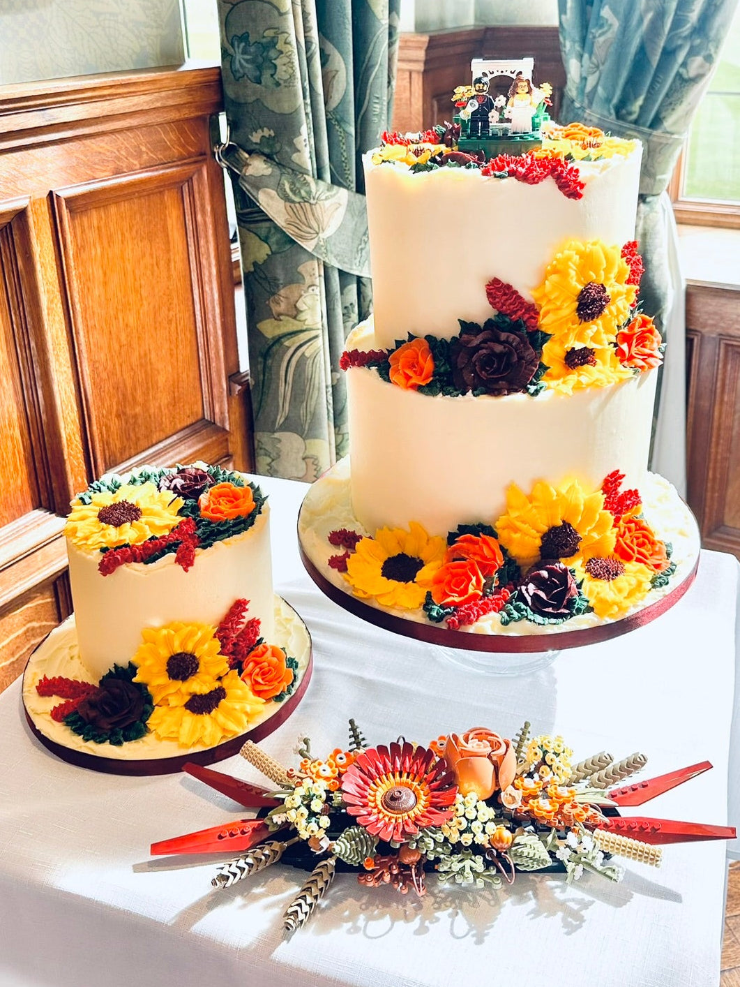 Two wedding cakes with floral decorations with a Lego Bride and Groom.